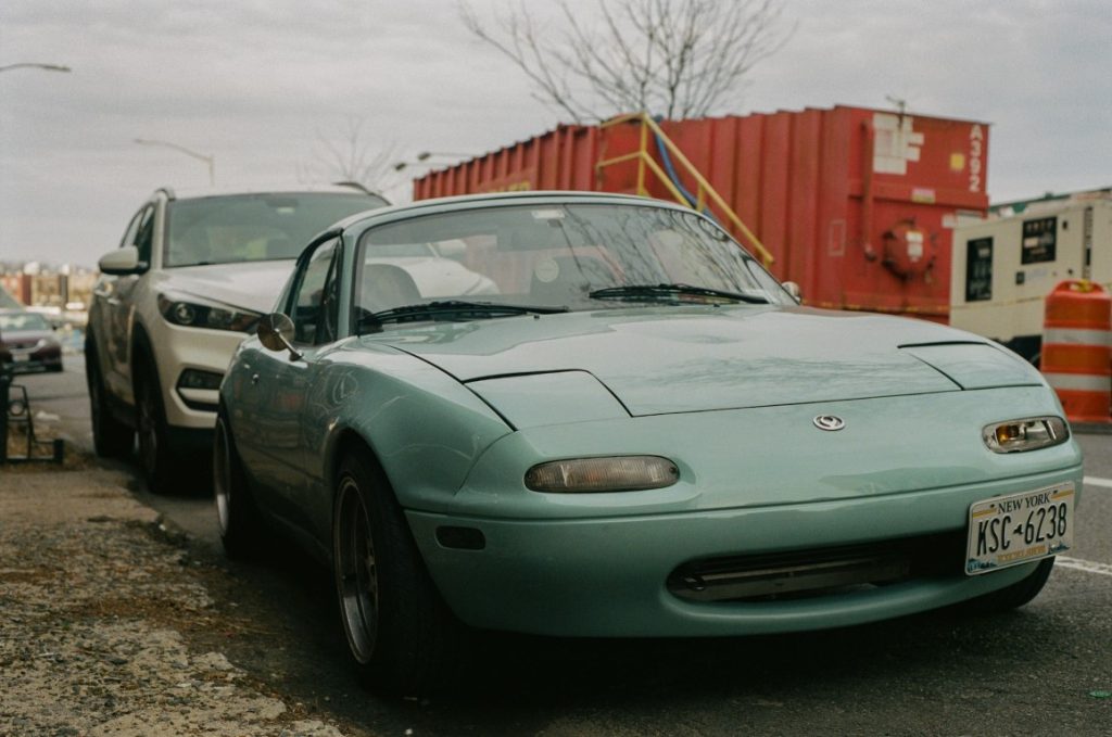 green miata parked on the road