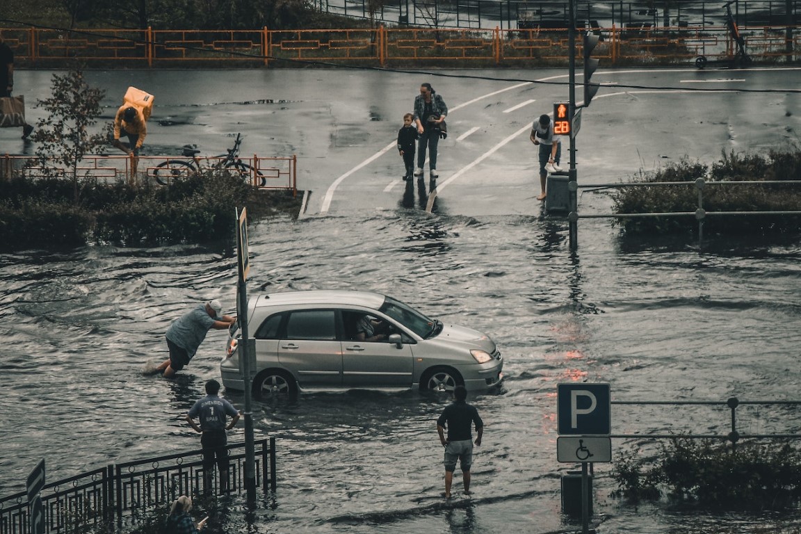 pushing a car up a road in a flooded street