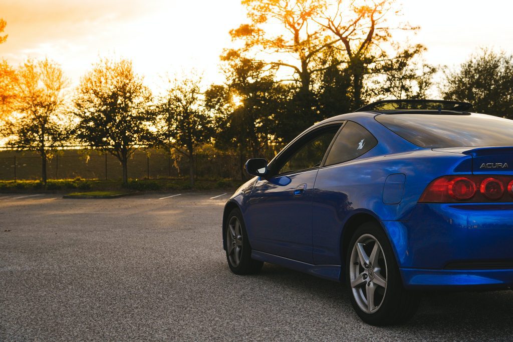 blue rsx parked in a lot with the sun going down