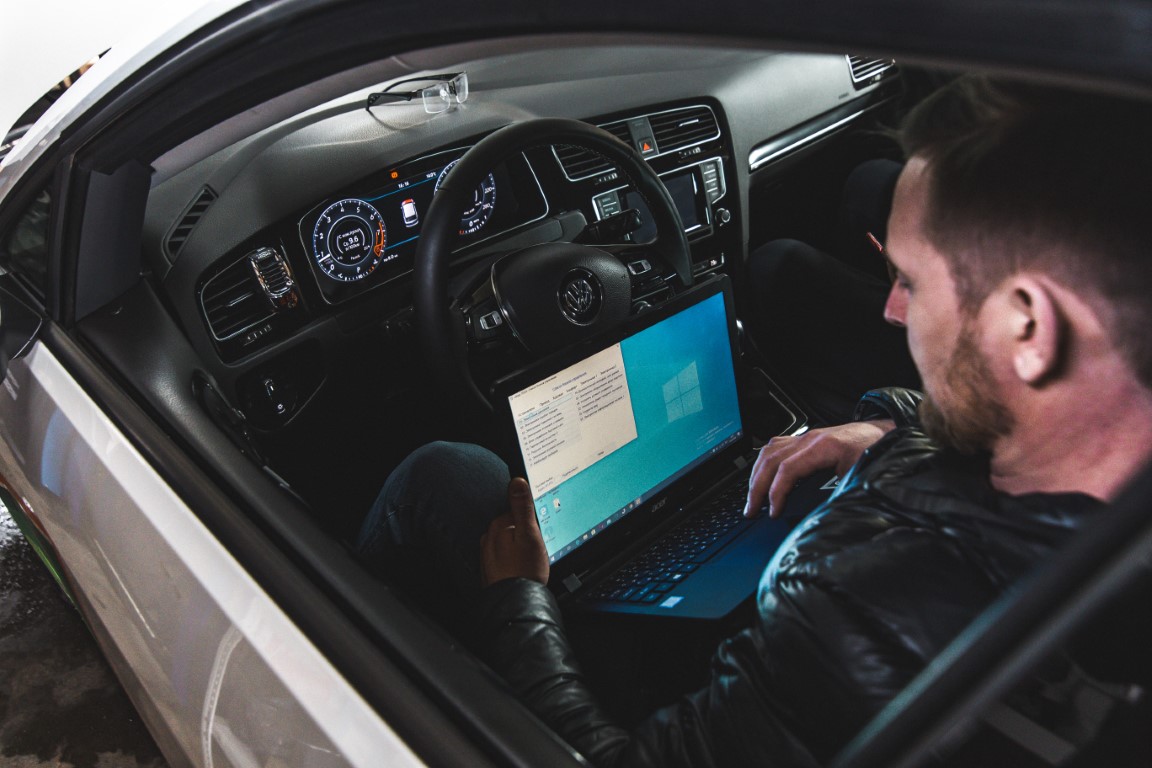 someone on a laptop checking out a car