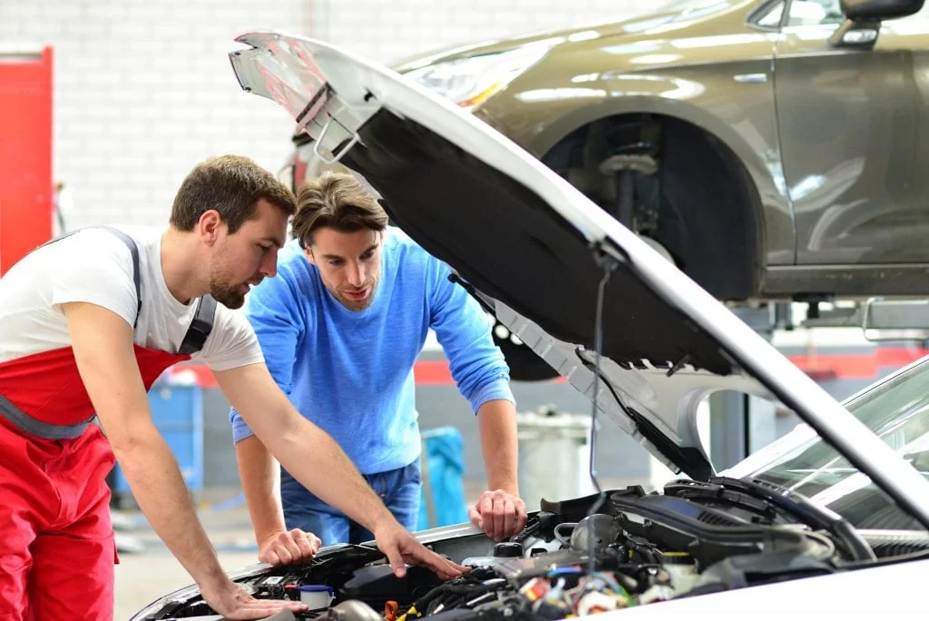 Mechanic and the owner checking the car engine