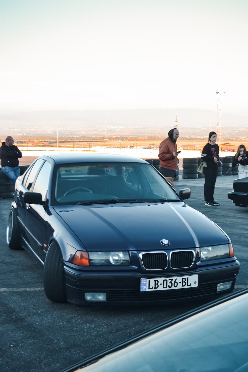 a car parked on pavement with people standing around