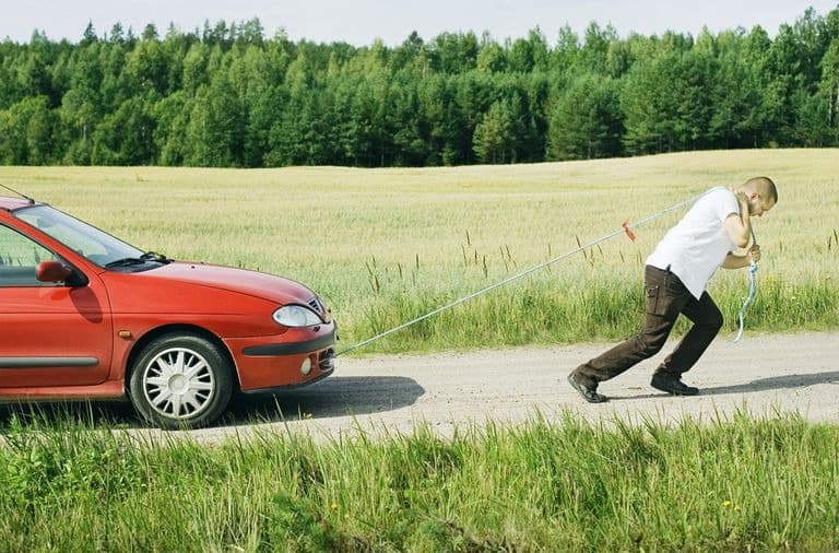 a person pulling a car after it broke down