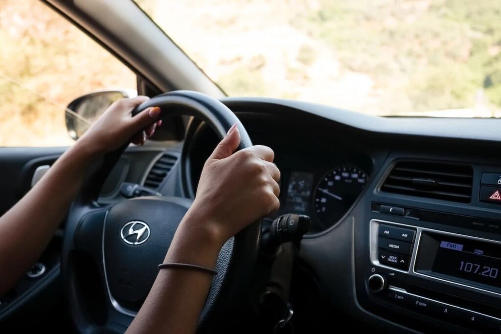 a person with two hands on the driving wheel of a Hyundai