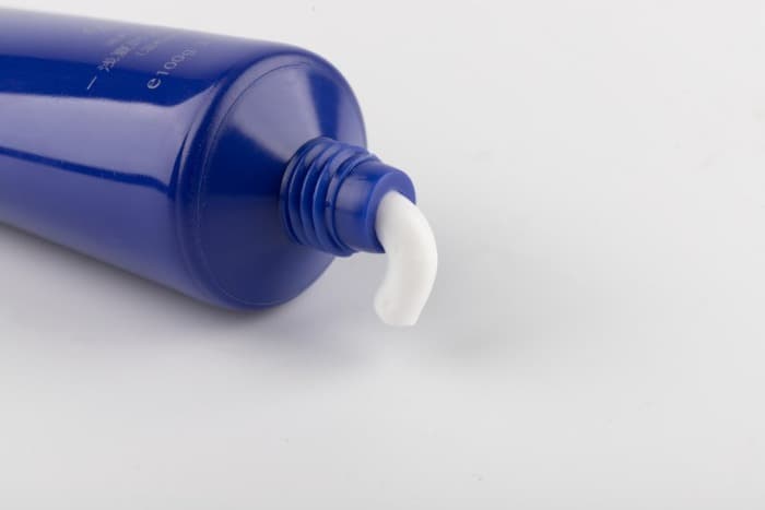blue and white plastic bottle with toothpaste
